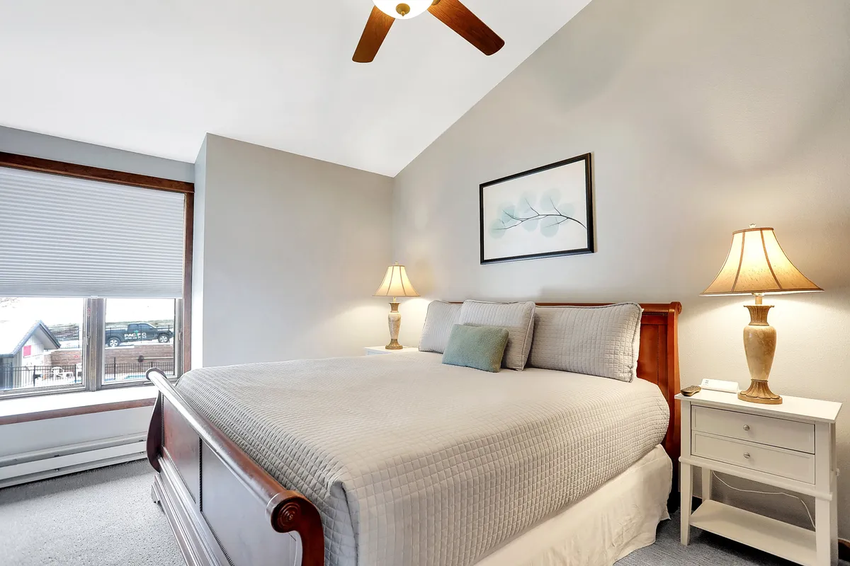 A serene bedroom featuring a cozy bed with soft linens, bedside lamps, tasteful artwork, and a window letting in gentle natural light. The room is uncluttered and offers an inviting atmosphere, ideal for restful sleep or quiet reading.