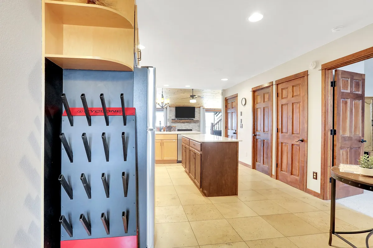 The image presents a different angle of the kitchen, focusing on the spacious kitchen island, modern refrigerator, and wide doorways opening to adjacent spaces. The scene feels bright, expansive, and welcoming—perfect for both cooking and socializing.